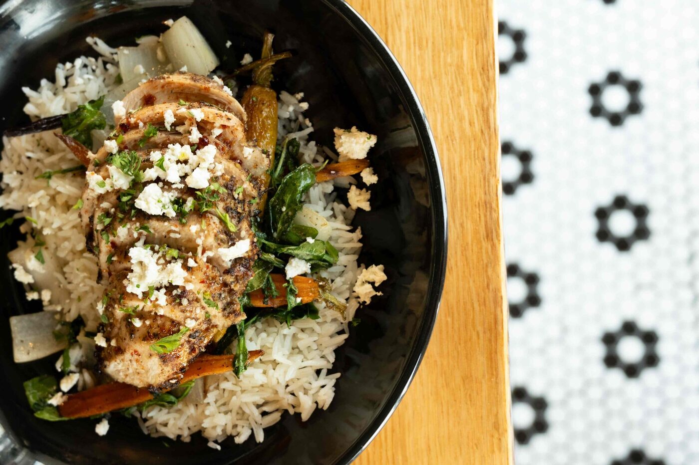 Herb-marinated chicken over green rice with feta and roasted carrots at bai-tee