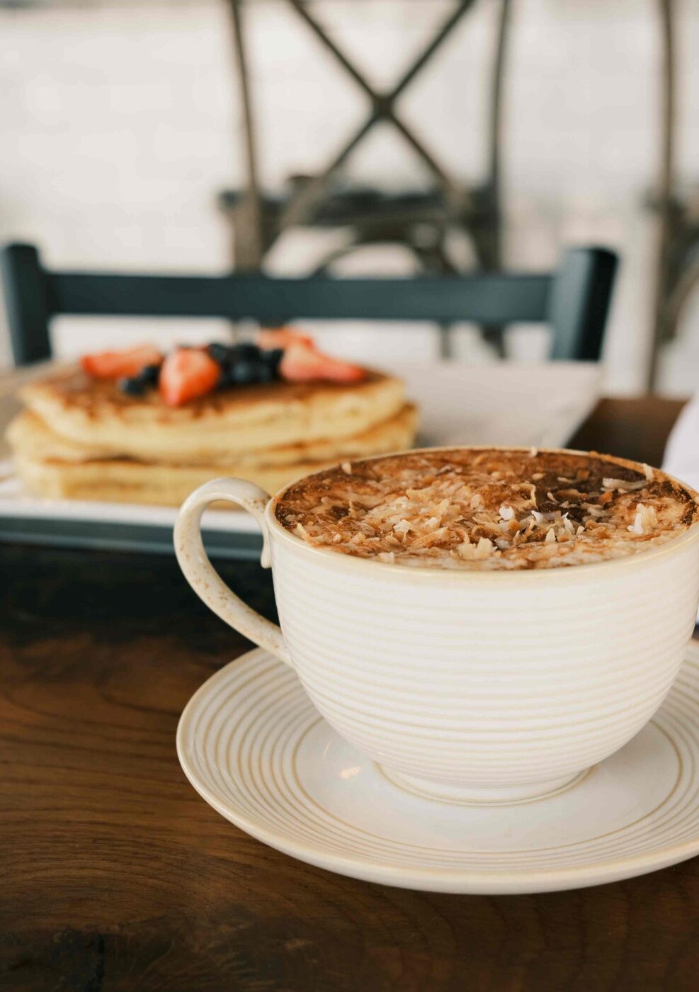Toasted coconut latte beside a stack of berry pancakes at bai-tee