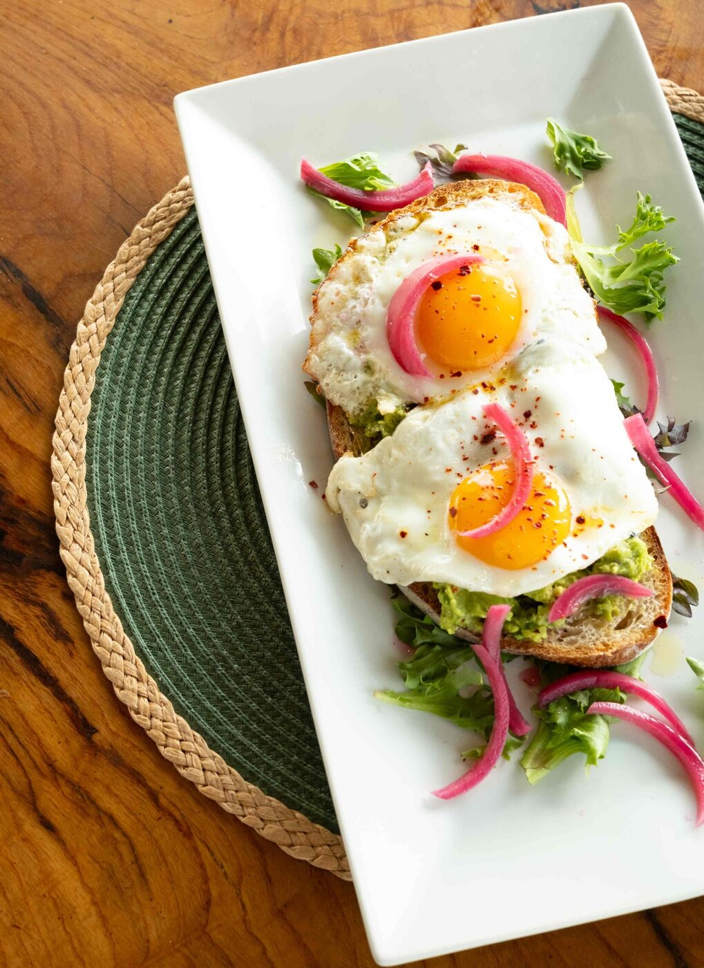 Avocado and fried egg tartine on house sourdough with pickled onion and greens at bai-tee
