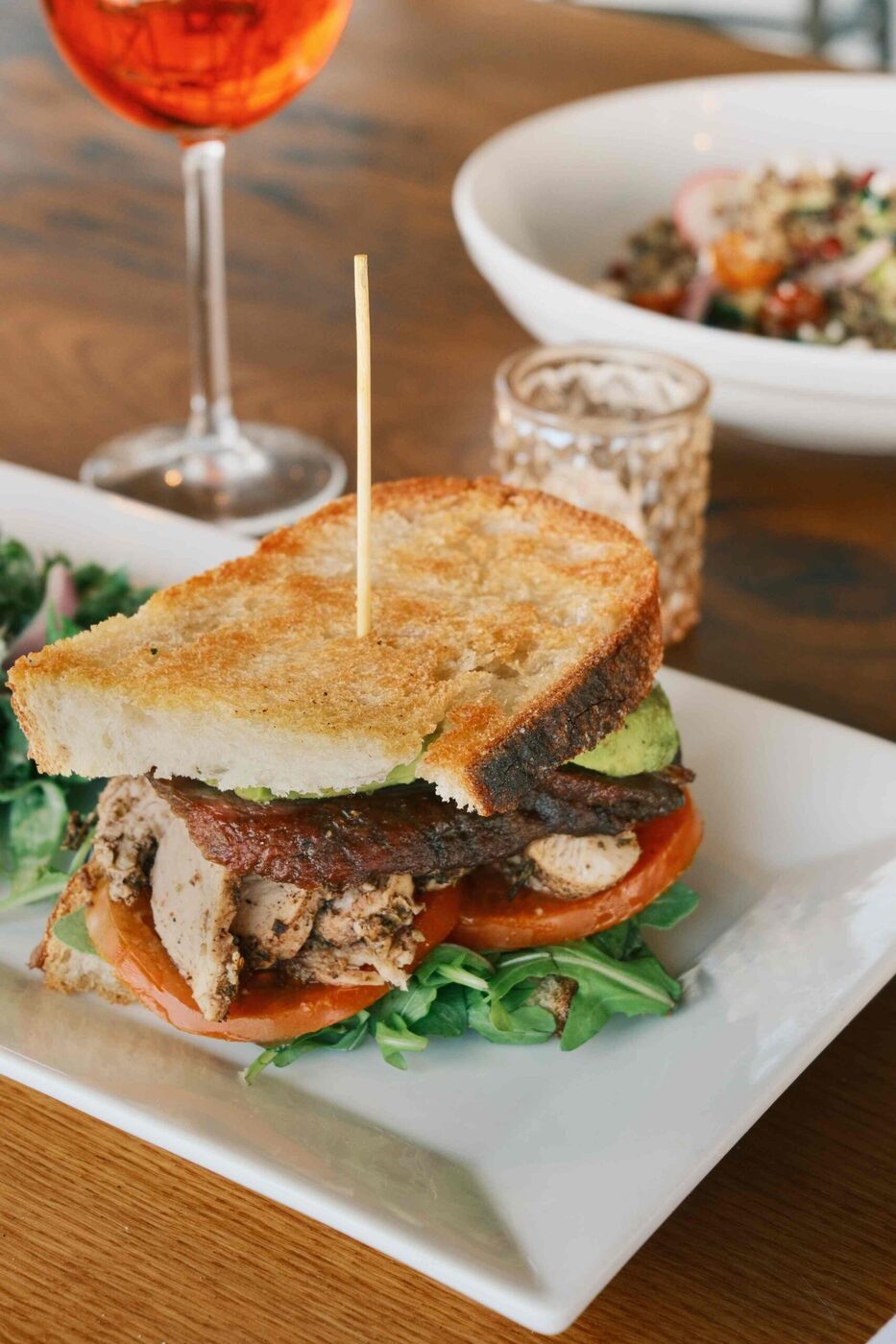 Grilled chicken sandwich on toasted sourdough with an Aperol spritz at bai-tee
