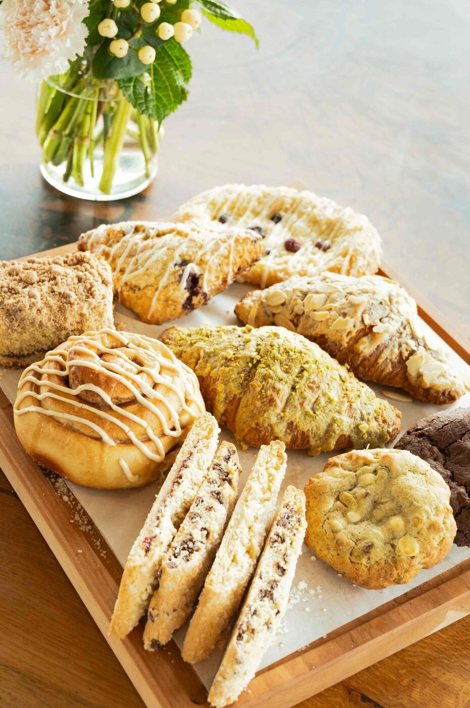 Board of fresh-baked pastries — cinnamon rolls, scones, pistachio croissant and biscotti at bai-tee