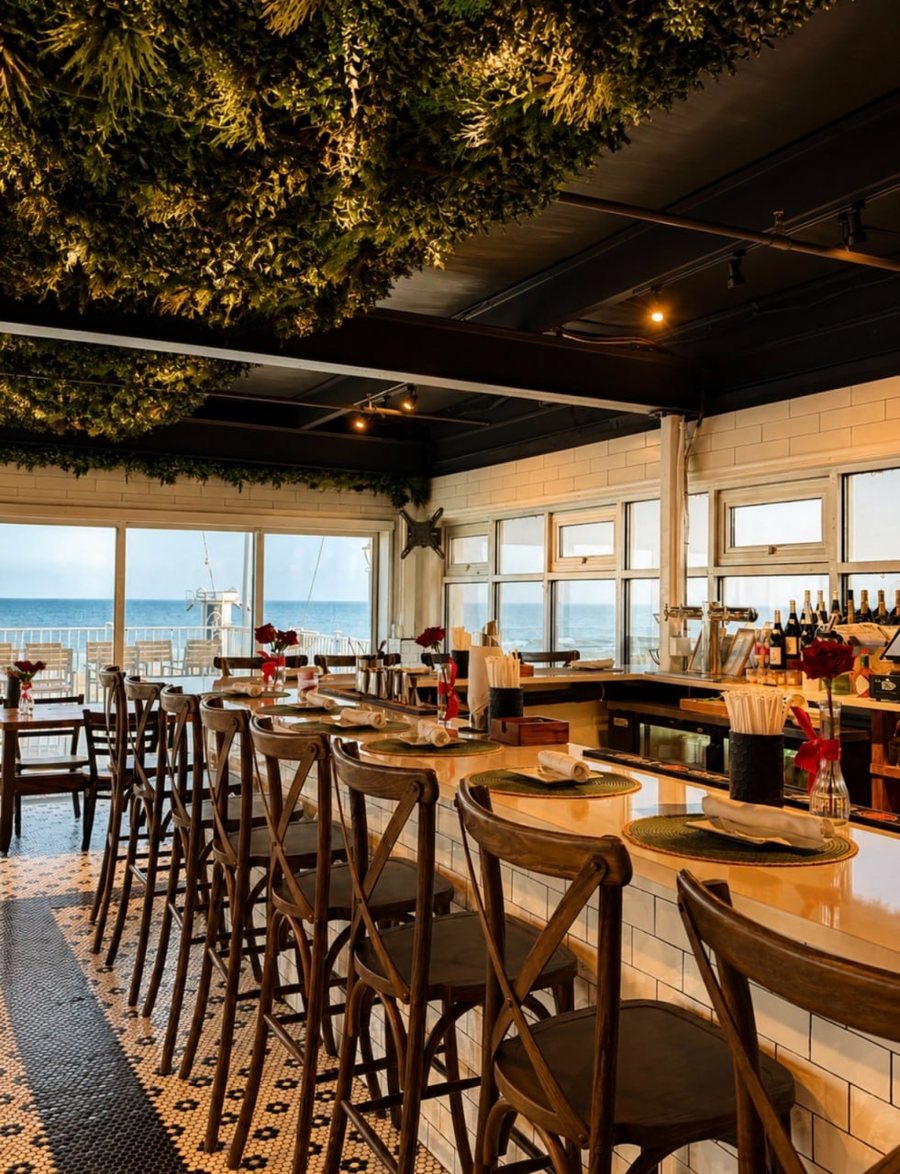 The bar at bai-tee at golden hour, beneath a living greenery ceiling with ocean views