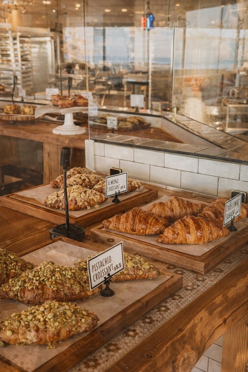 The bai-tee pastry case — almond and pistachio croissants fresh-baked on reclaimed wood counters